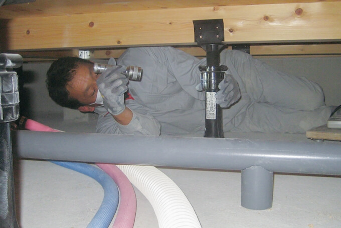 床下に潜って水道管のチェックを行う写真